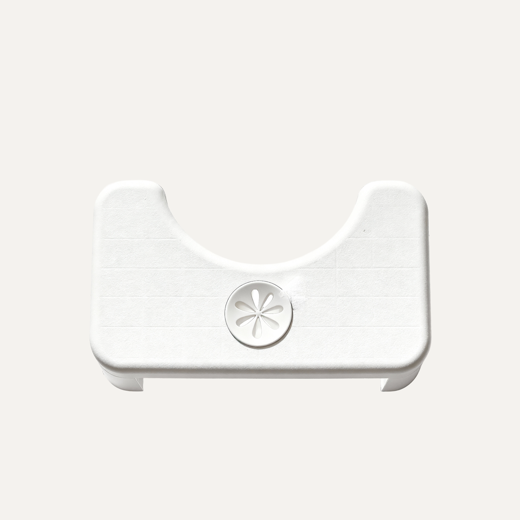 White plastic toilet stool with a central circular component known as a scent pocket on a light gray background
