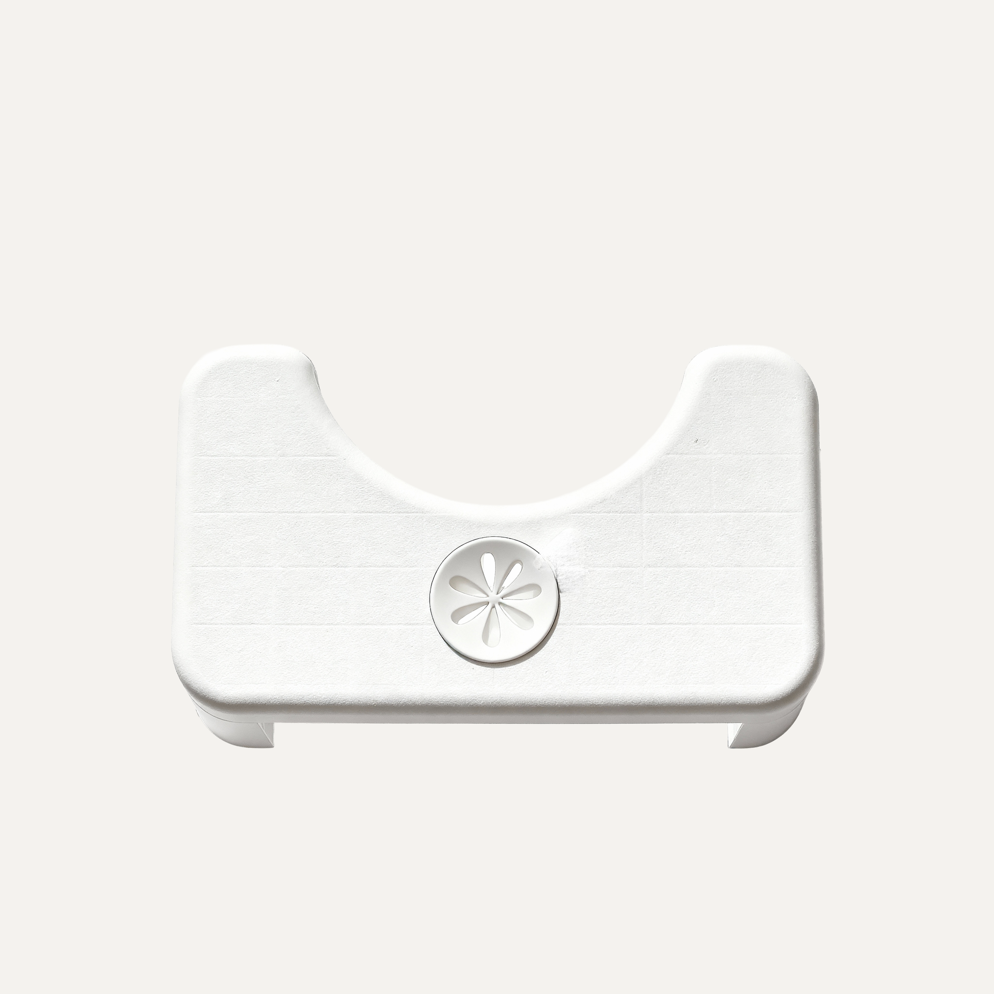 White plastic toilet stool with a central circular component known as a scent pocket on a light gray background